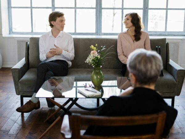 Relationship coach sitting in chair during coaching session with couple sitting on sofa