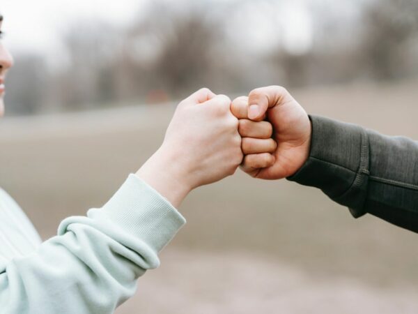 Assertiviteitscoach - Twee handen die elkaar een boks geven