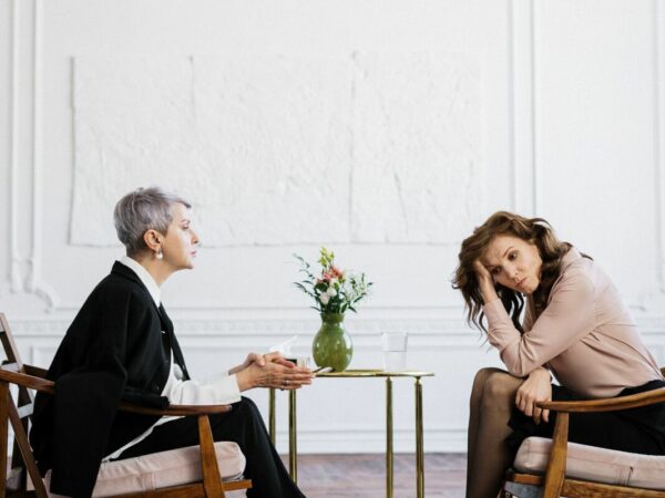 Burnout coach tijdens coaching sessie met haar vrouwelijke cliënt, beiden zittend in hun stoel