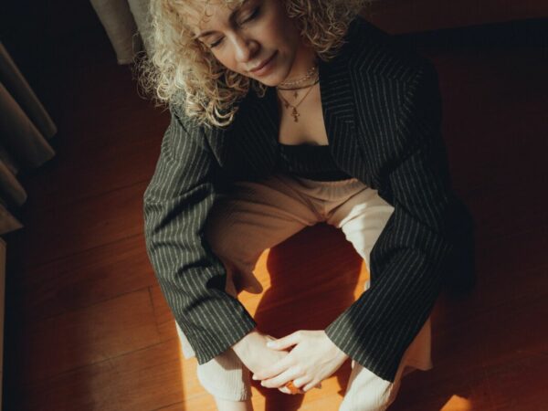 Vrouw zittend op de vloer in haar half donkere kamer
