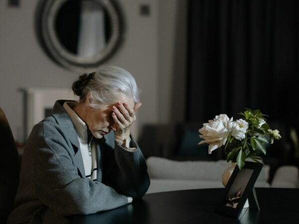 Grief coach - Sad woman sitting at the table, hand on her forehead