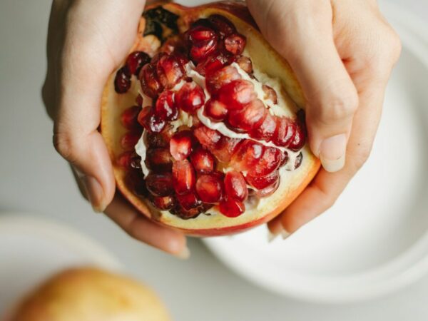 Voedingscoach - Twee handen die een doorgesneden granaatappel vasthouden