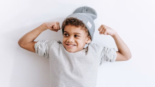 Child with hat poses with his 'muscle' for power kids